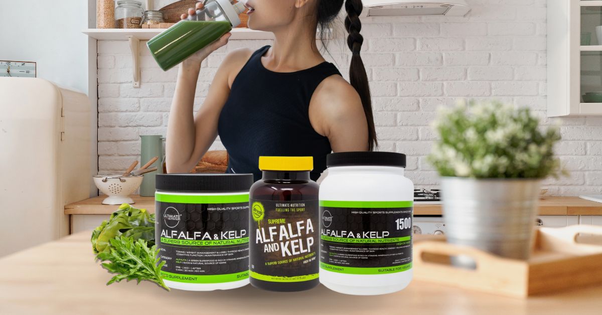 Ultimate Nutrition Alfalfa and Kelp supplement containers on a kitchen counter with fresh greens, while a person drinks a green smoothie in the background.